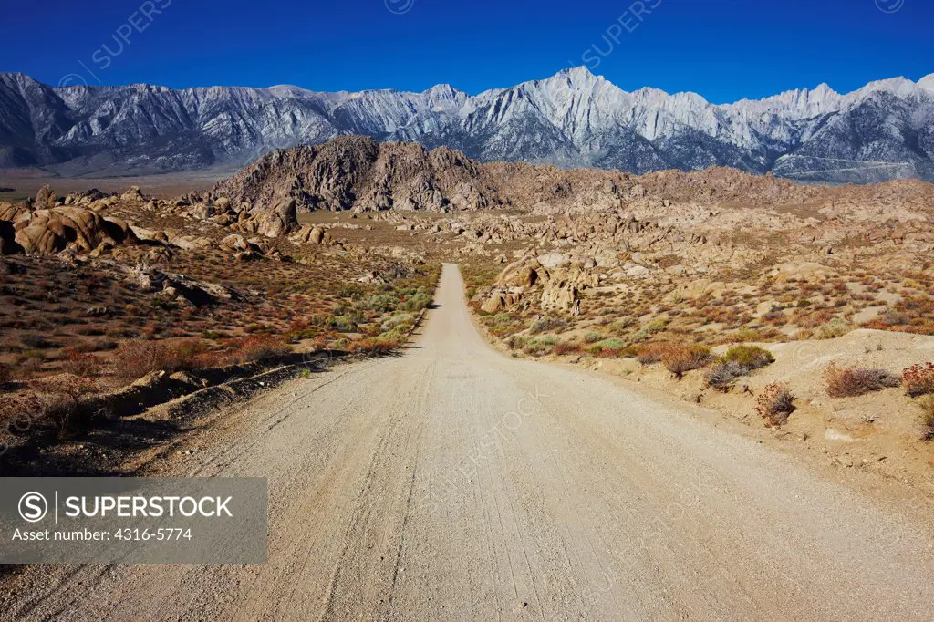 USA, California, Sierra Nevada, Dirt road through Alabama Hills, distant Mount Whitney and Mount Lone Pine