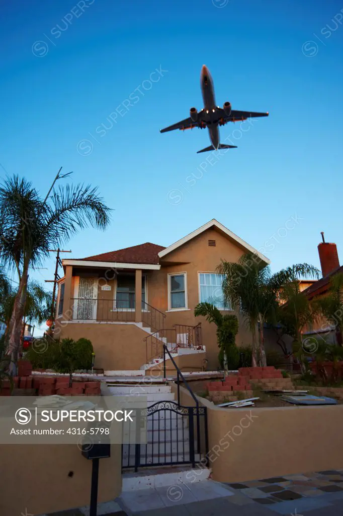 USA, California, San Diego, Jet airliner flying low over house