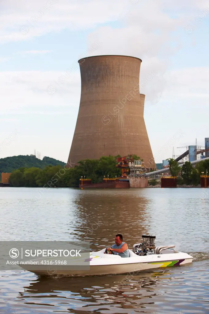 USA, West Virginia, Poca, Man in speedboat beneath cooling towers of John E. Amos Power Plant