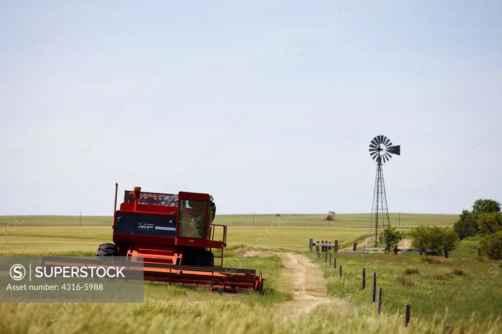 USA, Kansas, Wheat combine and windmill on ranch