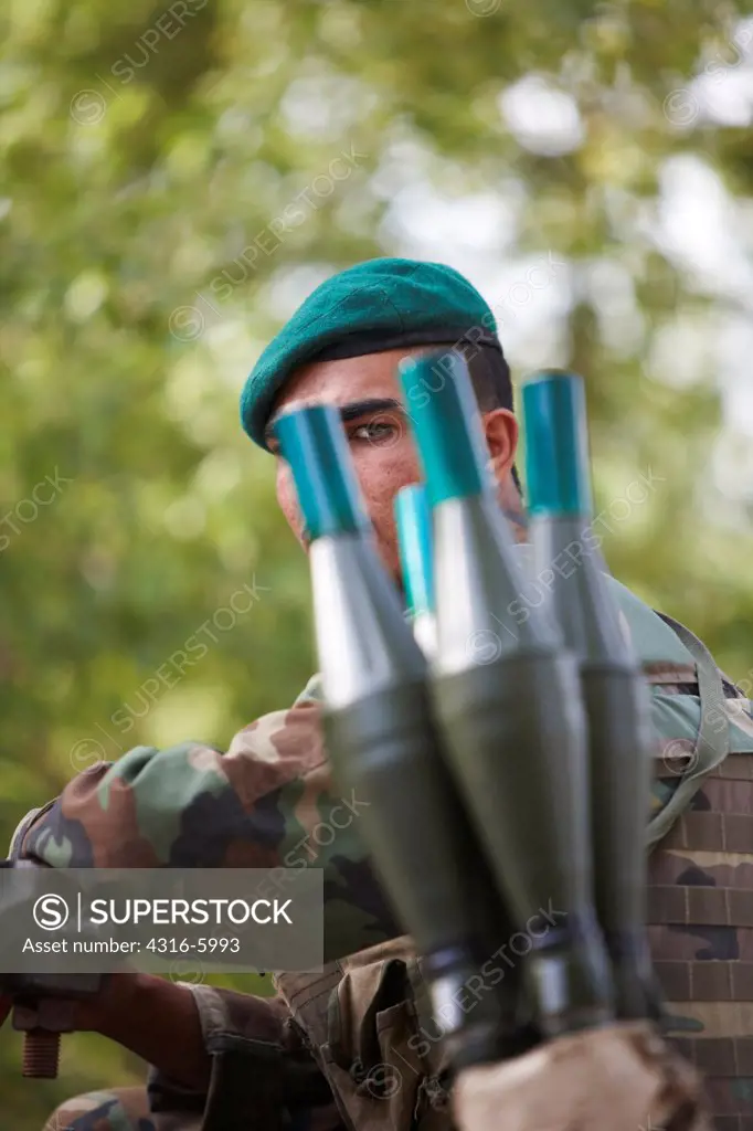 Afghanistan, Kunar Province, Afghan National Army soldier peering through bunch of live rocket propelled grenades
