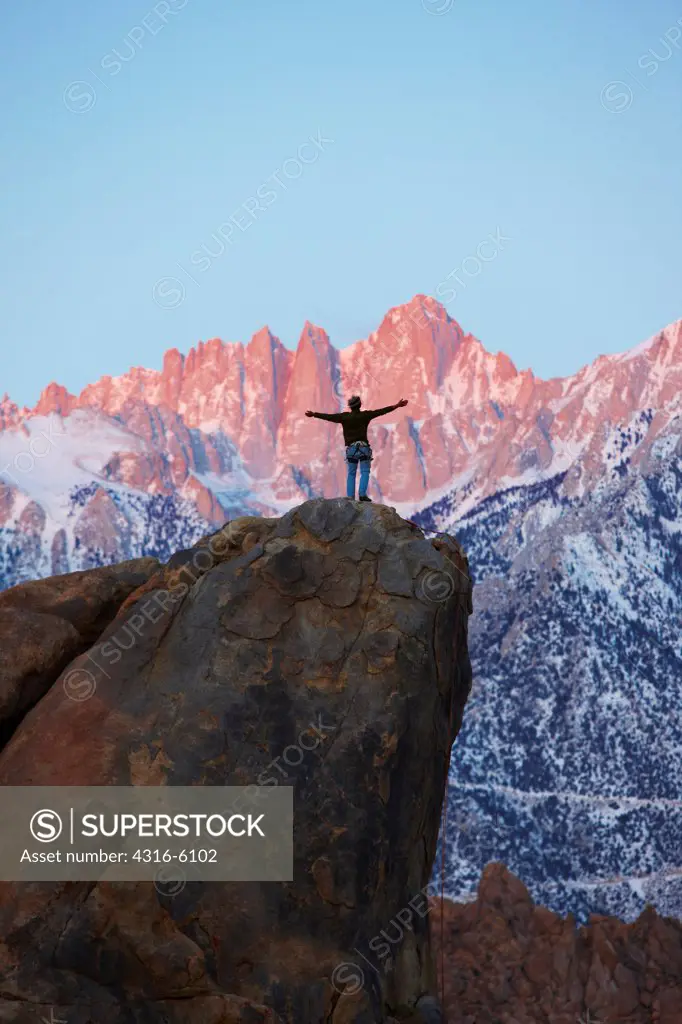 USA, California, Alabama Hills, Rock climber standing on boulder with Mount Whitney in distance