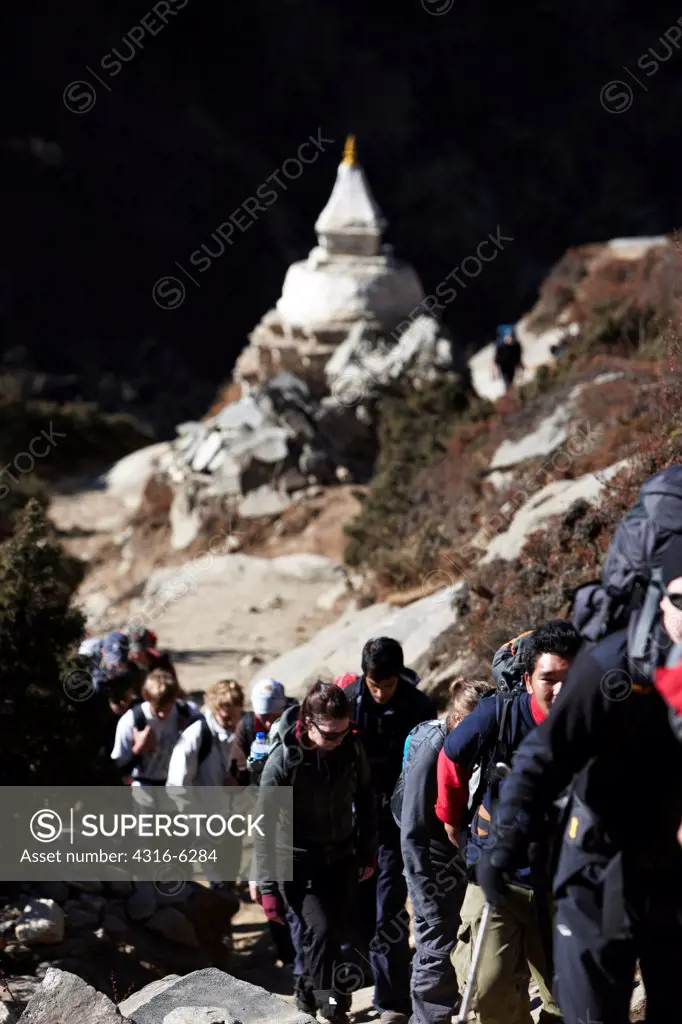 Nepal, Himalaya, Solukhumbu District, Khumbu, line of trekkers and Nepalese Sherpa porters passing Tibetan Buddhist Stupa