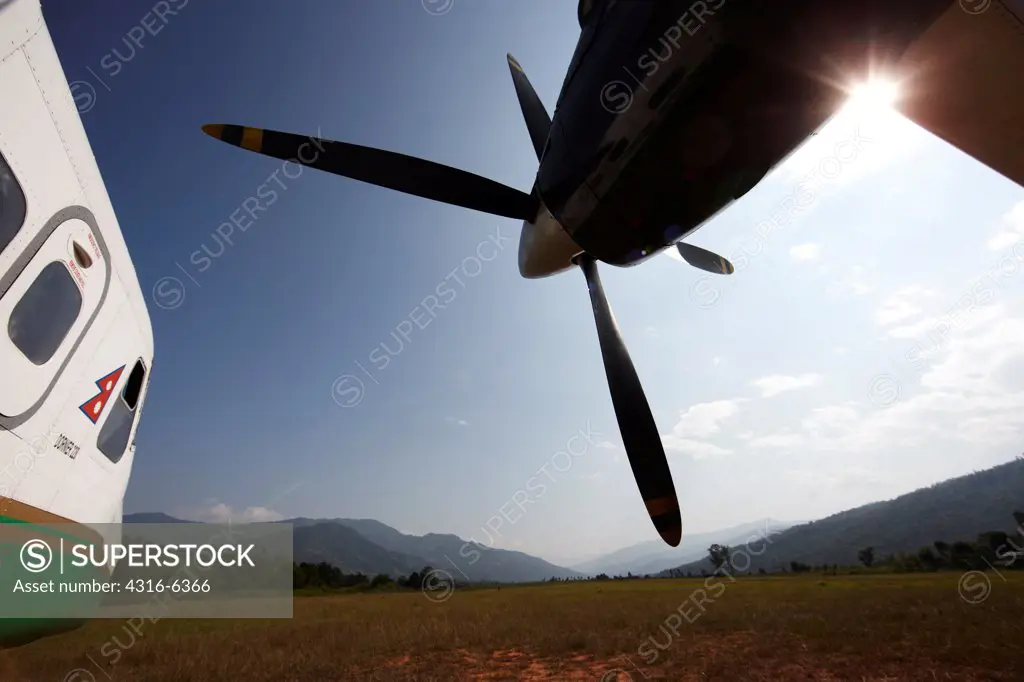 Nepal, Himalaya, Tumlingtar, twin-turboprop passenger aircraft on dirt airstrip, wide angle view