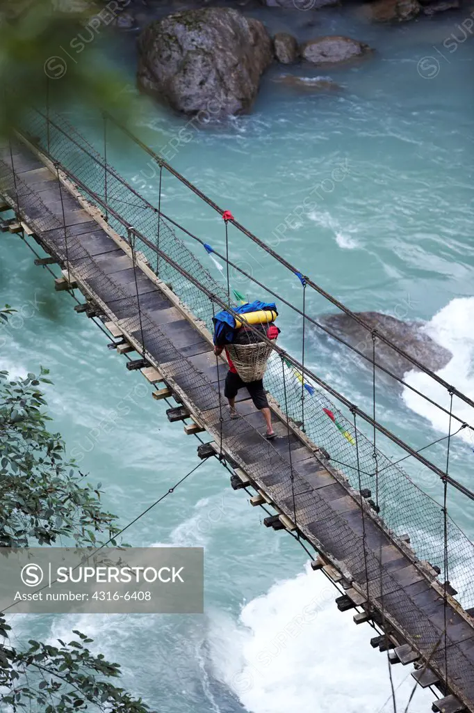Nepal, Himalaya, Arun Rive, Sherpa porter crossing suspension bridge