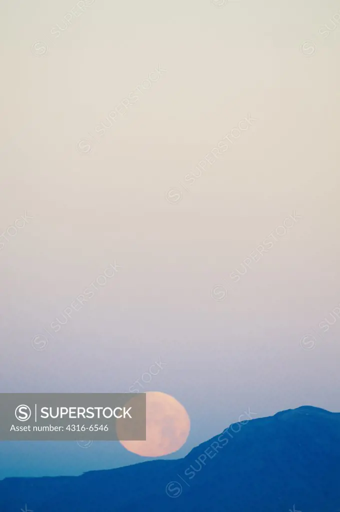 Rising full moon on mountain ridge, Tularosa Basin, Alamogordo, New Mexico, USA