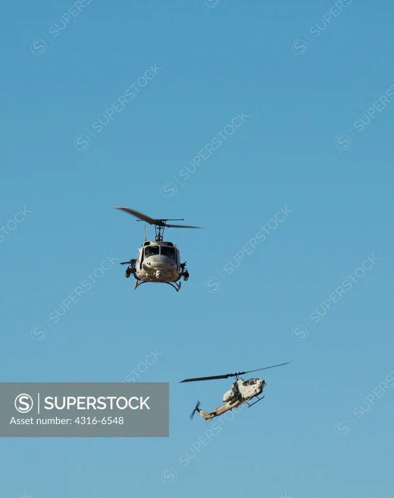 US Marine Corps UH-1N Iroquois Utility Helicopter fitted with rockets and machine guns for an attack mission and a Marine Corps AH-1W SuperCobra attack helicopter maneuver during close air support training at Yodaville, Barry M. Goldwater Air Force Range, Arizona, USA