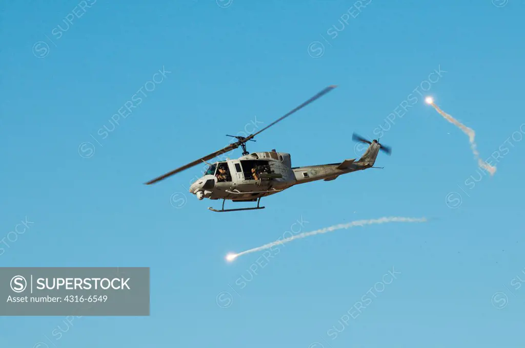 US Marine Corps UH-1N Iroquois Utility Helicopter fitted with rockets and machine guns for an attack mission expends flares during close air support training at Yodaville, Barry M. Goldwater Air Force Range, Arizona, USA