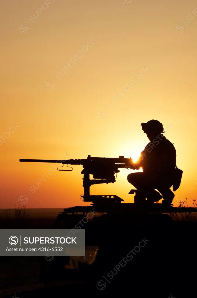 Silhouette of a US Marine manning an M2 .50 caliber machine gun