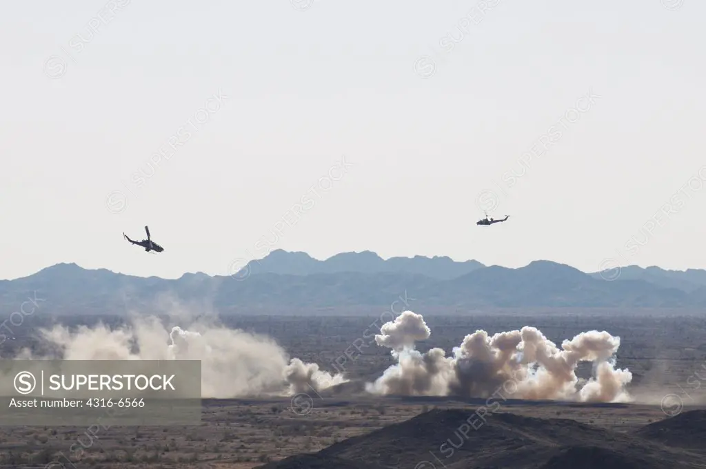 US Marine Corps AH-1W SuperCobra attack helicopter and a Marine Corps UH-1N Iroquois utility helicopter fitted with machine guns and Hydra 70 rockets attack a target on the floor of the desert at the Chocolate Mountain Aerial Gunnery Range, California, USA