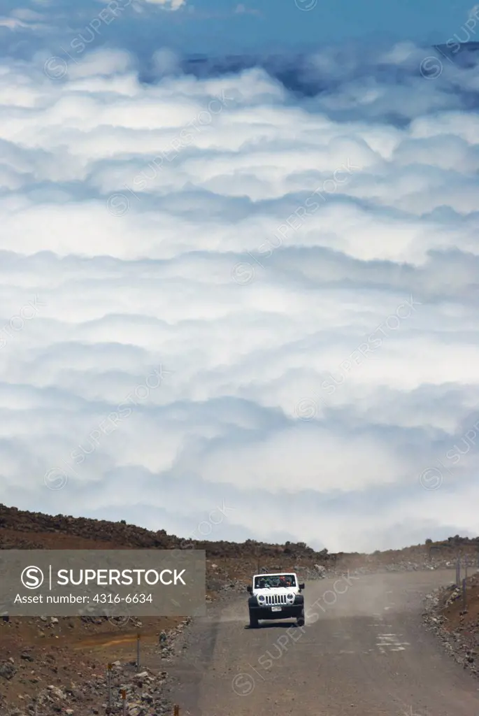 Jeep ascends the unpaved section of the John A. Burns Way near the summit of Mauna Kea, Hawaii County, Hawaii, USA