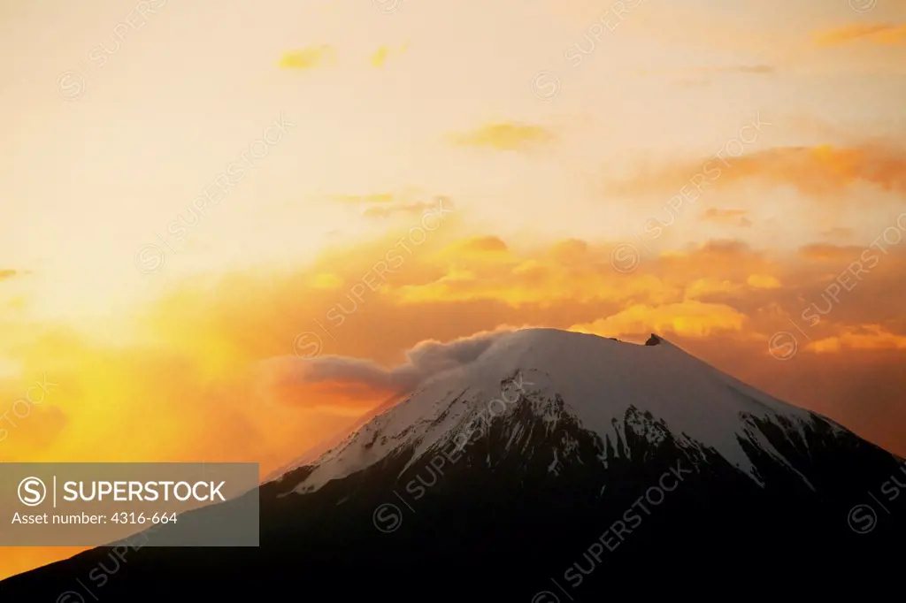 The Colors of Sunset Erupt on Clouds Above One of the Payachatas Volcanoes