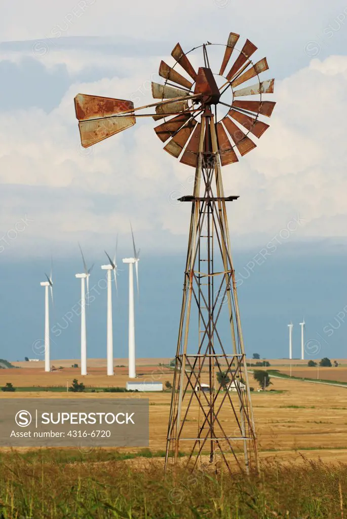 Juxtaposition of old damaged Aeromotor water pumping windmill and distant modern electricity producing wind turbines, Weatherford Wind Energy Center, Weatherford, Oklahoma, USA