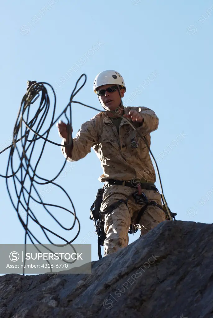 US Marine during mountain warfare training throws a rope over a cliff preparing to rappel down the cliff, Mountain Warfare Training Center, Bridgeport, California, USA