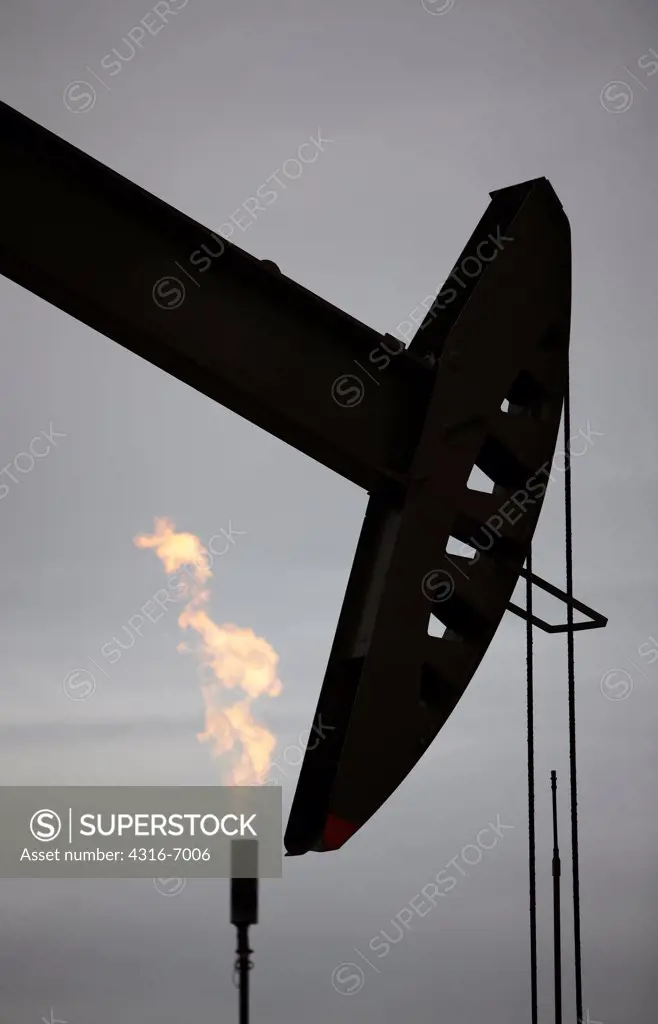 USA, Colorado, Oil well pumpjack and flaring tower