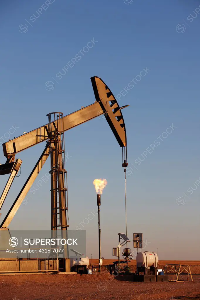 Oil well pumpjack and gas flare in the eastern plains of Colorado, USA