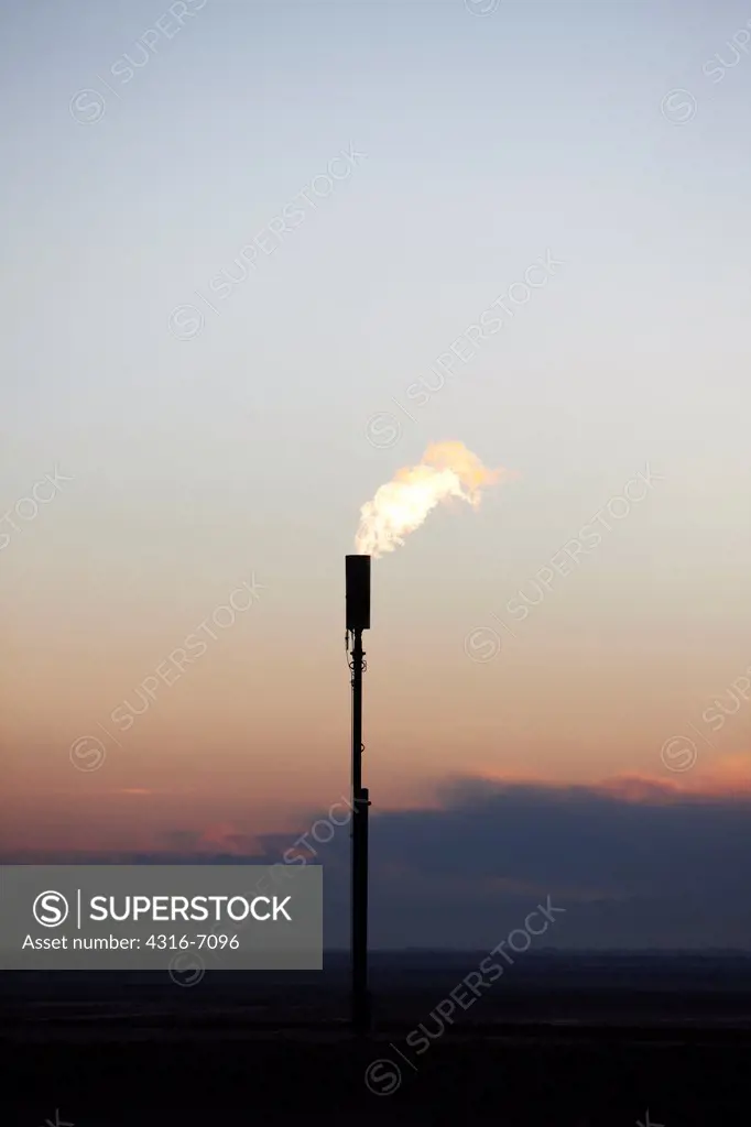 Gas flare at sunset, eastern plains of Colorado, USA