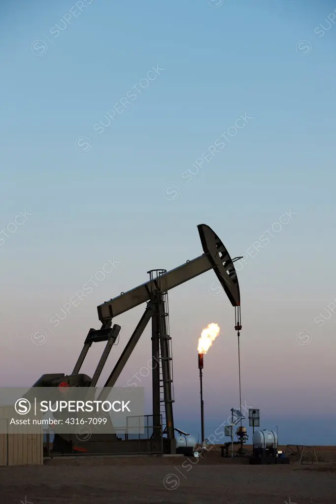 Oil well pumpjack and gas flare in the eastern plains of Colorado, USA