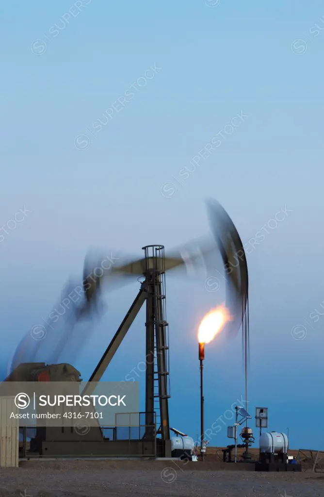 Oil well pumpjack and gas flare in the eastern plains of Colorado, USA