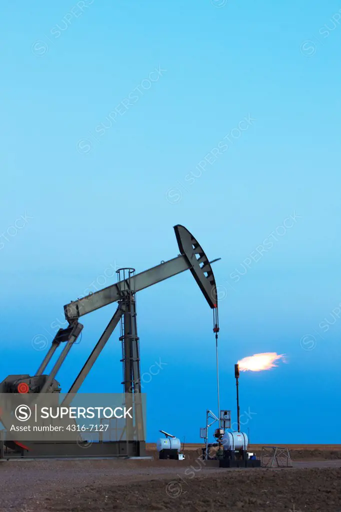 USA, Colorado, Oil well pumpjack (pump jack) and gas flare (flare stack), Oil well developed with hydraulic fracturing, also known as hydrofracking or fracking