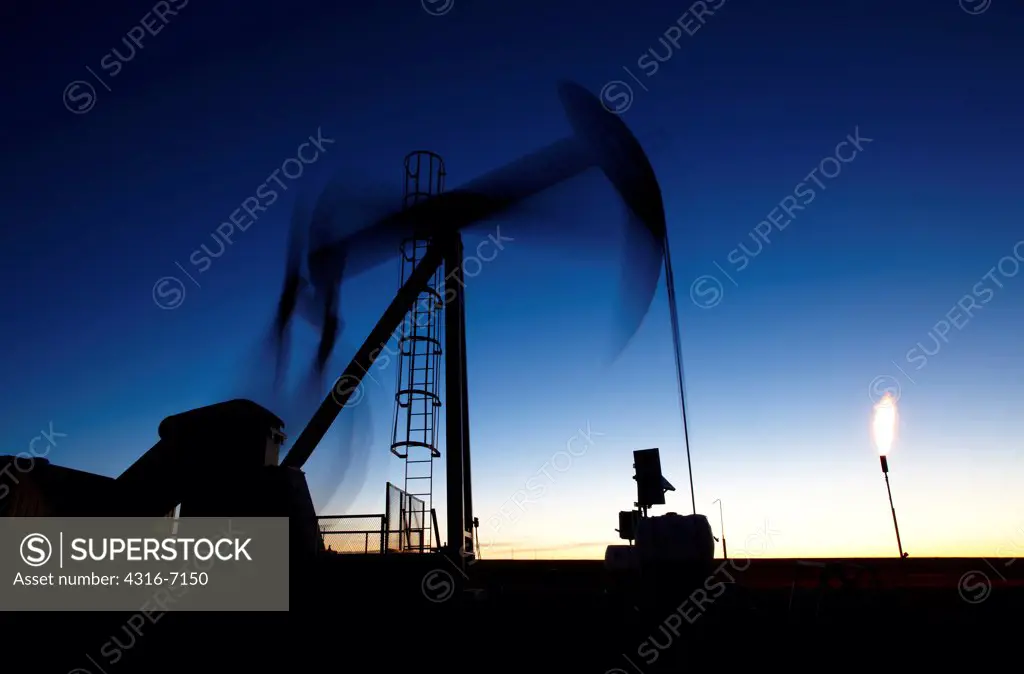 USA, Colorado, Oil well pumpjack (pump jack) and gas flare (flare stack)