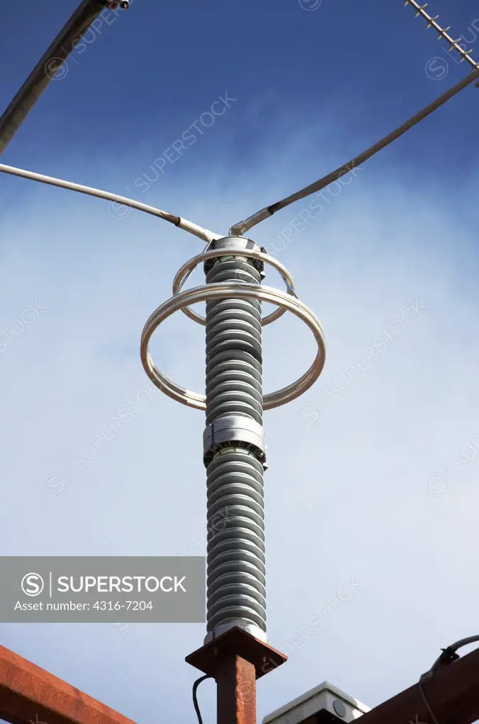 insulator on high voltage electricity transmission tower with grading rings (corona or anti-corona rings) around insulator