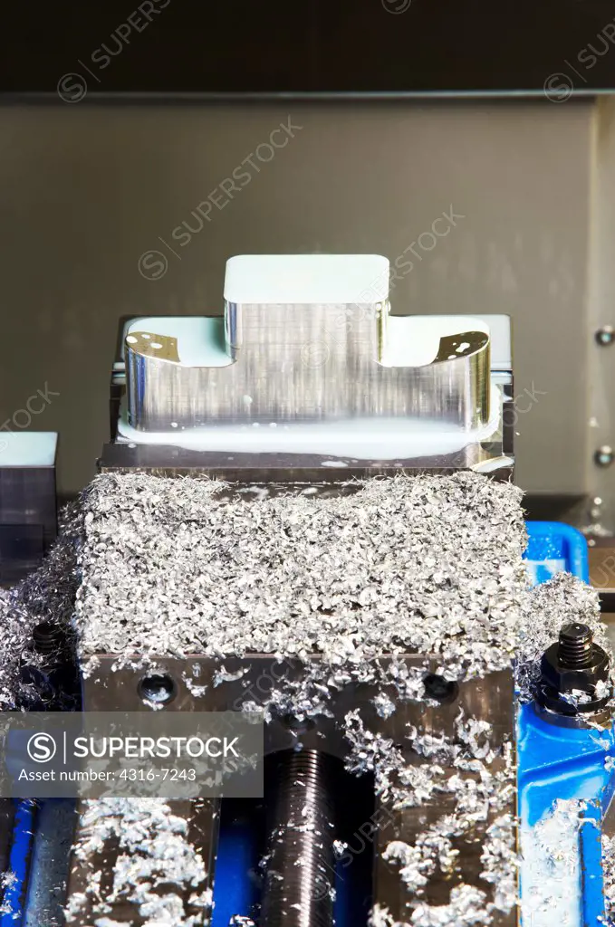 Ingot or block, of 7075 aluminum partially machined into part for aircraft, in three axis CNC (computer numerical control) milling machine with metal shavings