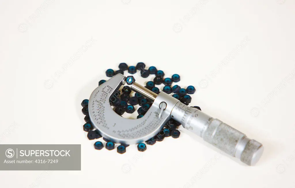 Black anodized nylon locking nuts, known as nylocs, or nyloc insert lock nuts, with caliper micrometer