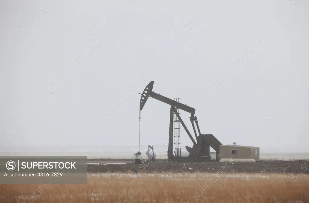 USA, Colorado, Eastern Plains of Colorado, Oil well pump jack in blizzard, fracking, hydrofracking