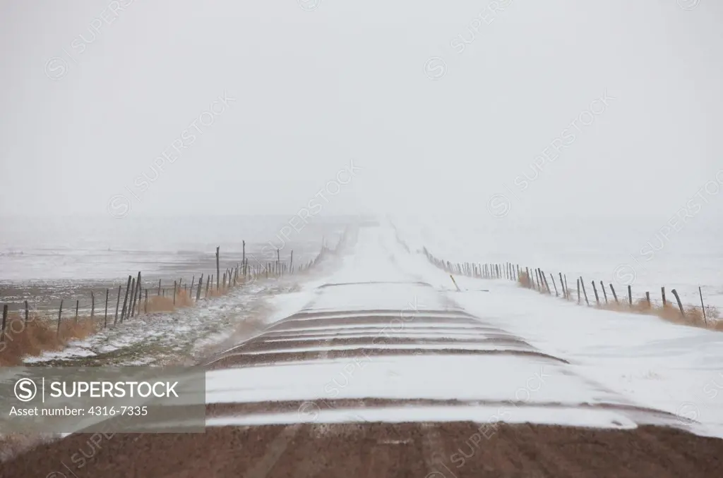 USA, Colorado, Eastern Plains of Colorado, Dirt road partially covered in wind-driven snow during blizzard