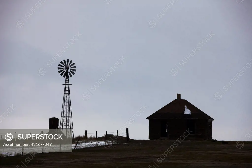 USA, Colorado, Eastern Plains of Colorado, Abandoned ranch house and windmill, clearing blizzard