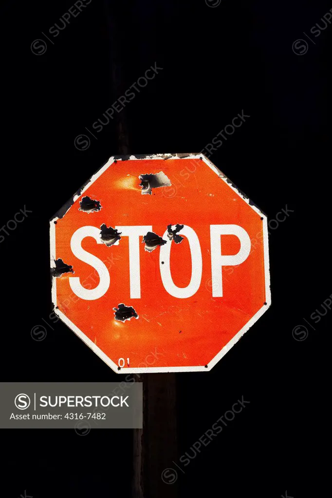 Stop sign, riddled with bullet holes