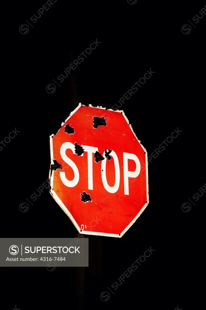 Stop sign, riddled with bullet holes