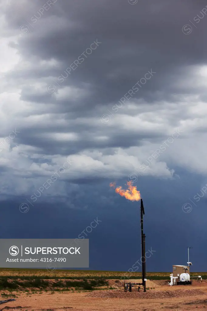 Flare stack at the site of an oil well, with a distant violent thunderstorm during a tornado watch, Colorado
