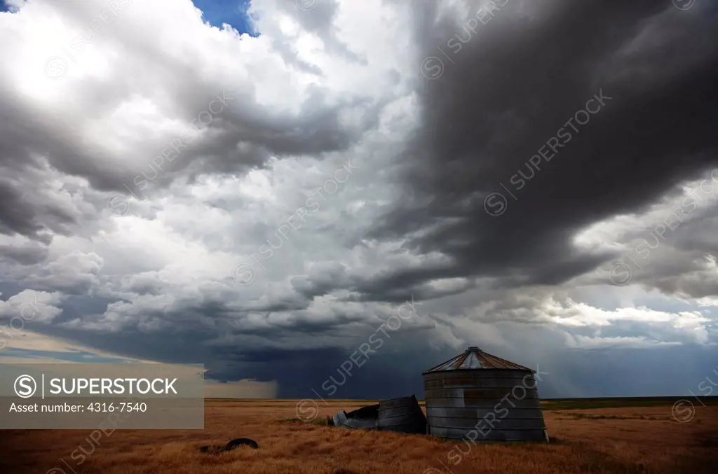 Old, decaying grain bins on plains with approaching powerful thunderstorm that produced a funnel cloud.