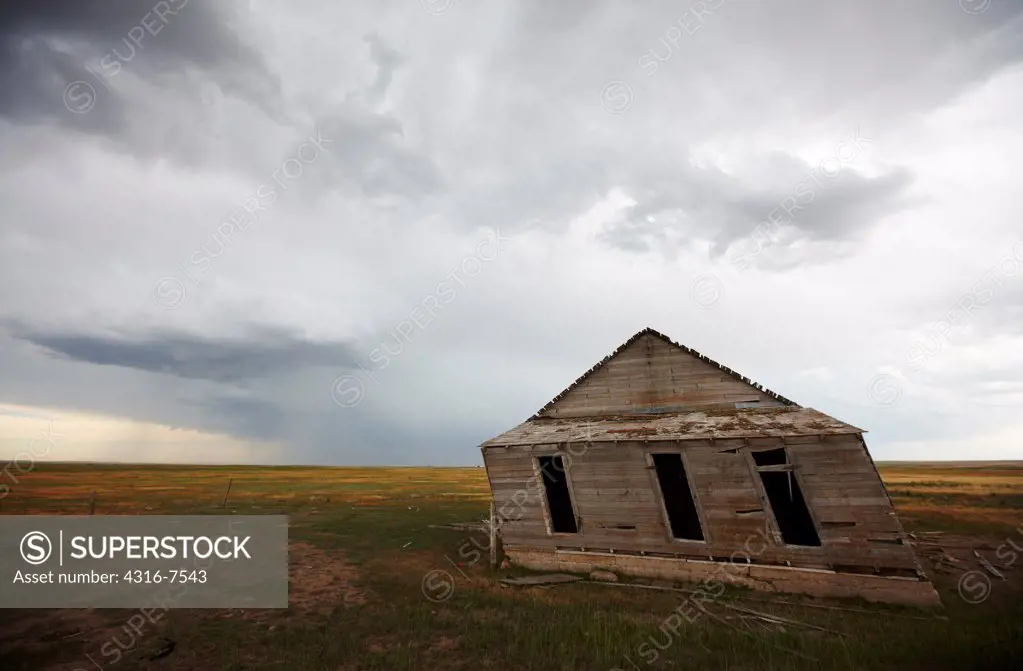 Old, abandoned, decaying barn on prairie and approaching powerful thunderstorm that spawned a funnel cloud, Colorado