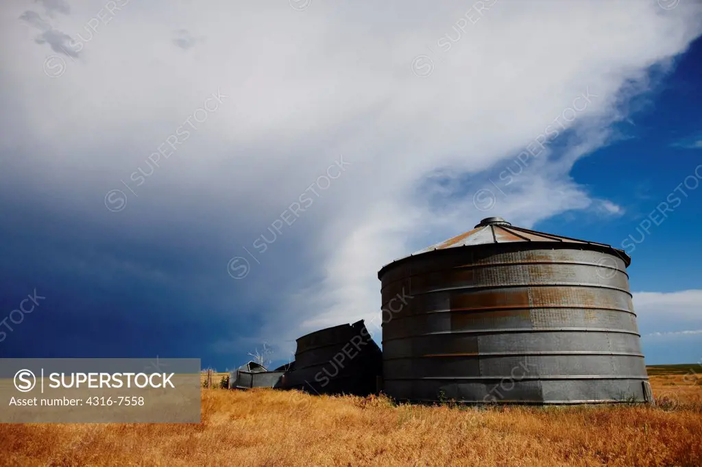 Old, decaying grain bins on plains with approaching powerful thunderstorm that produced a funnel cloud.
