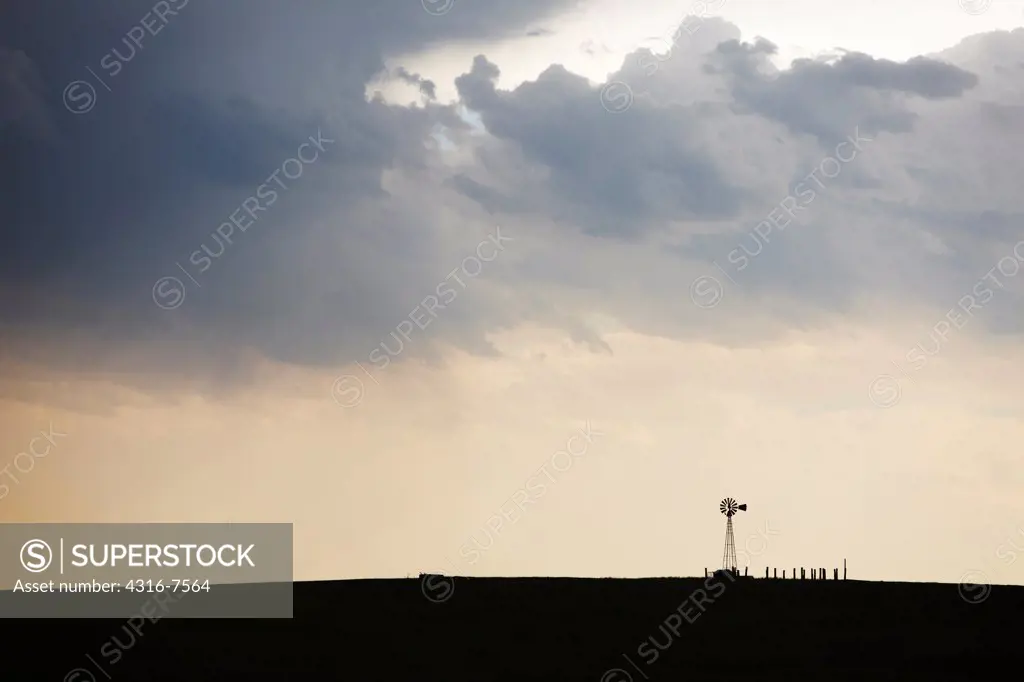 Crepuscular rays, also known as god beams, shine down toward a lone windmill after the passage of a powerful thunderstorm, Colorado.