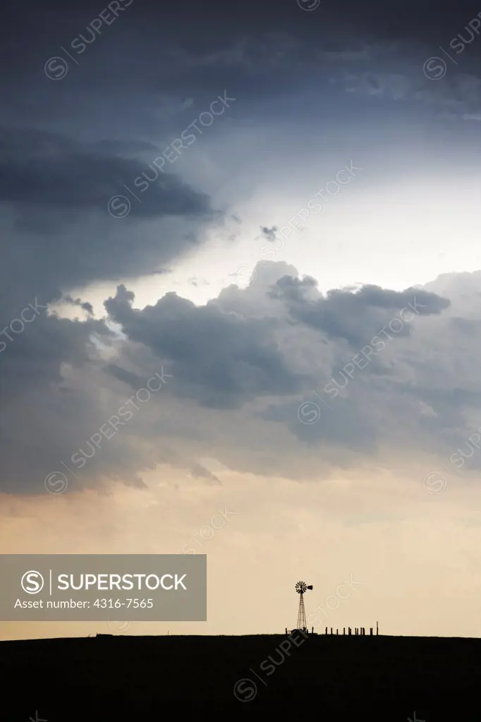 Crepuscular rays, also known as god beams, shine down toward a lone windmill after the passage of a powerful thunderstorm, Colorado.