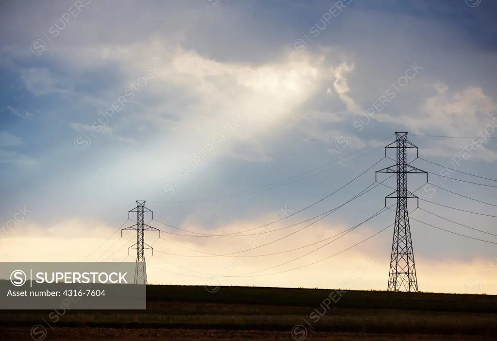 Passing thunderstorm, afternoon light, crepuscular rays (God Beams), line of high voltage power line transmission towers, Colorado