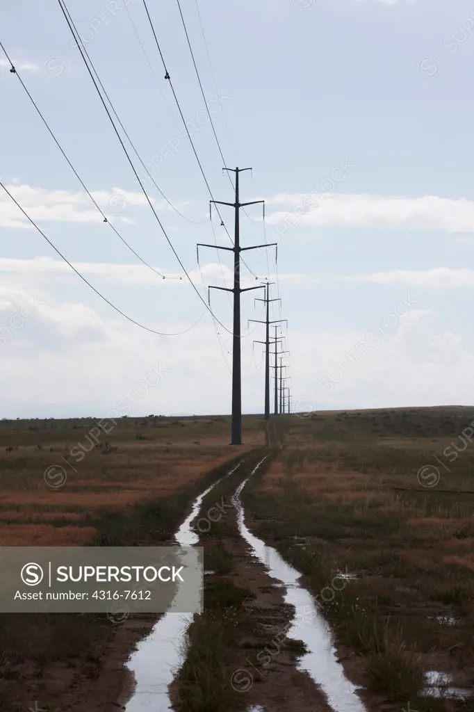 Two track dirt road, water logged, under high voltage power lines and transmission towers, after an intense rain storm, Colorado