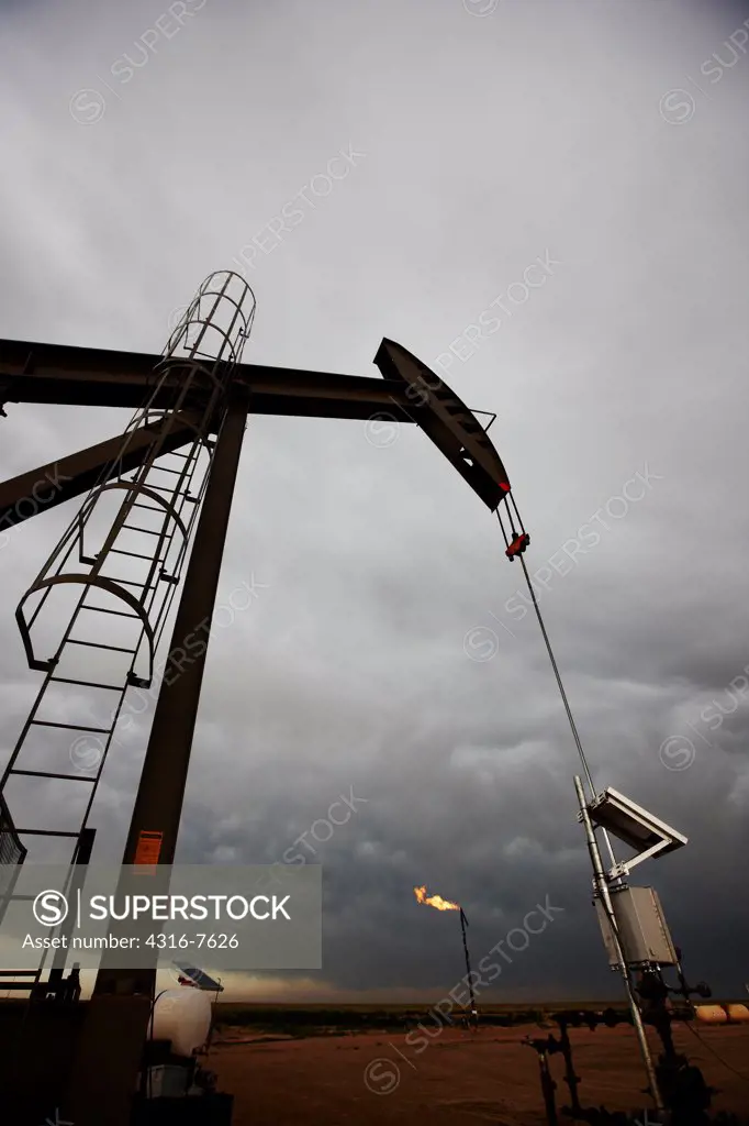 Oil well pump jack and flare stack releasing burning natural gas, Colorado