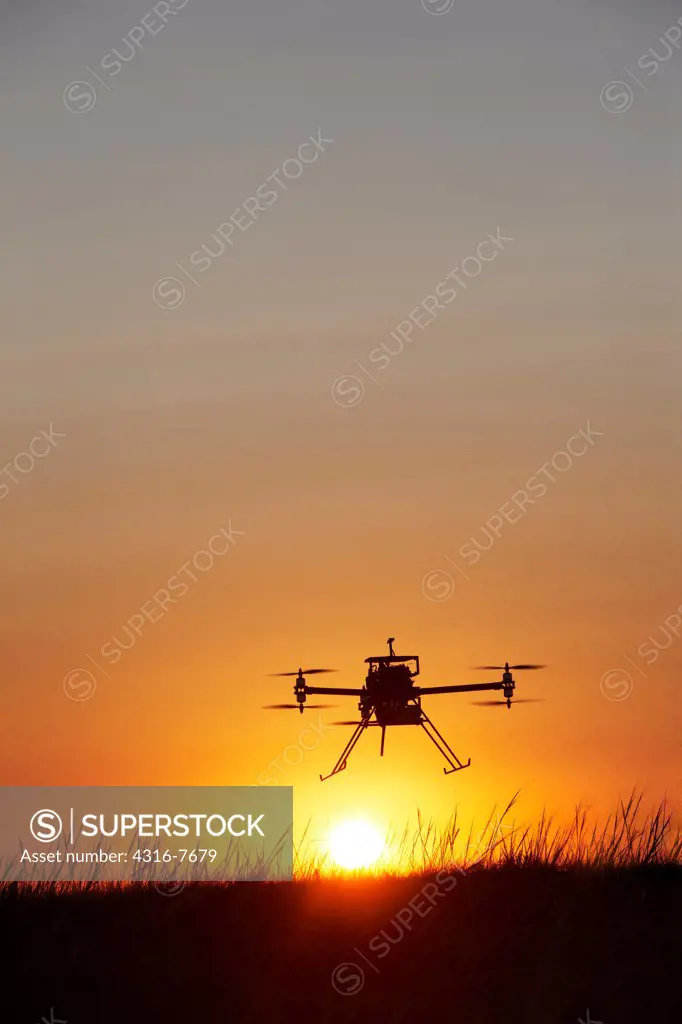 Unmanned aerial vehicle (UAV) or drone, In flight, Silhouetted by rising sun