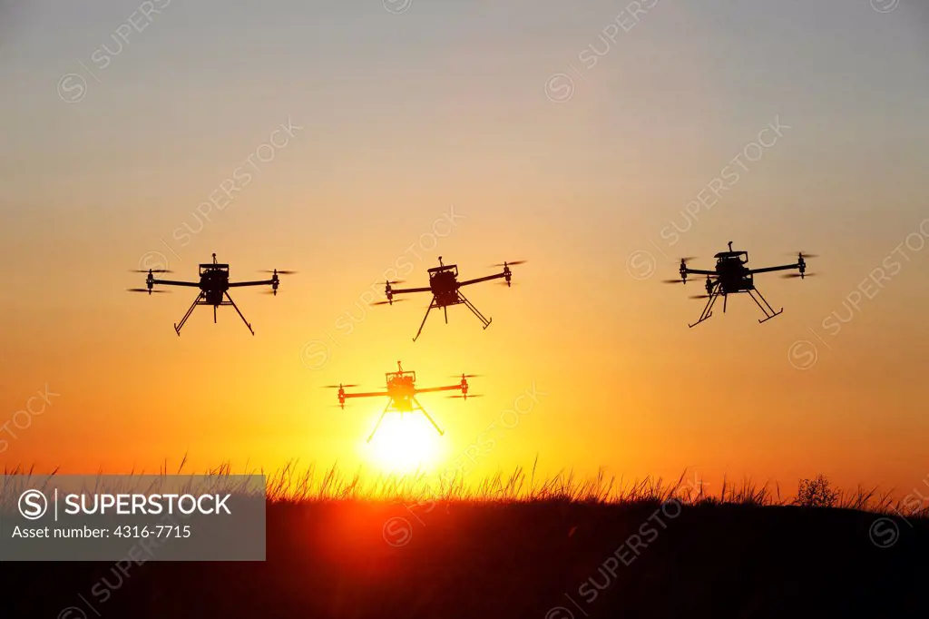 Four unmanned aerial vehicles (UAVs) or drones, In flight, Rising sun, Silhouettes