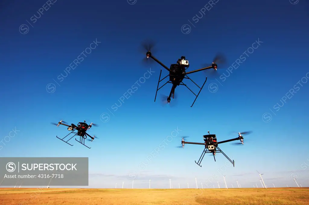 Three quickly approaching unmanned aerial vehicles (UAVs) or drones
