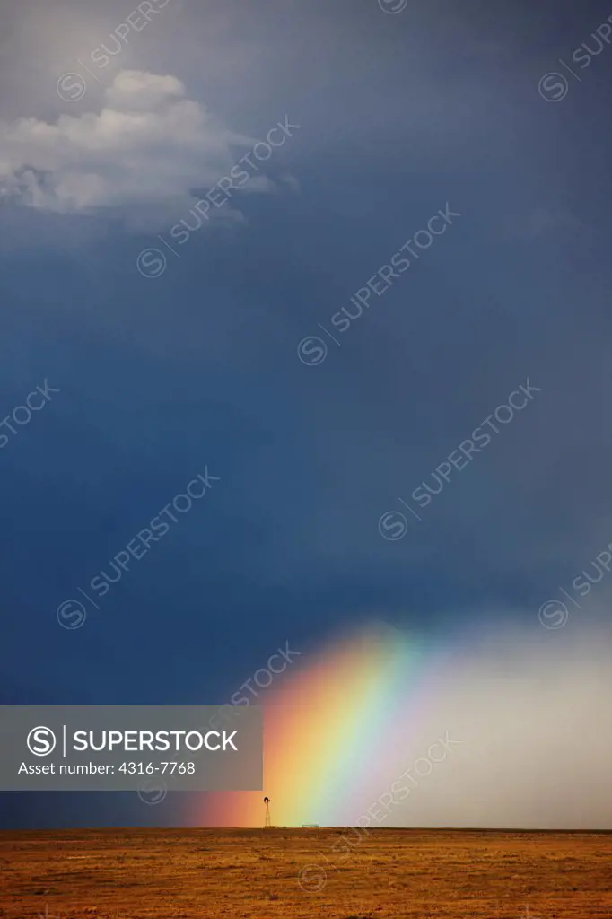 USA, Colorado, Rainbow, and curtains of rain at base of powerful thunderstorm, ending at lone windmill on open plains