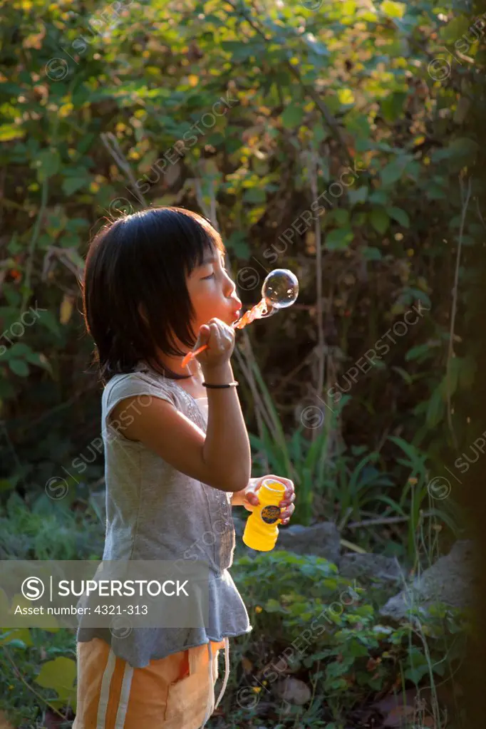 Girl blowing bubbles in a garden