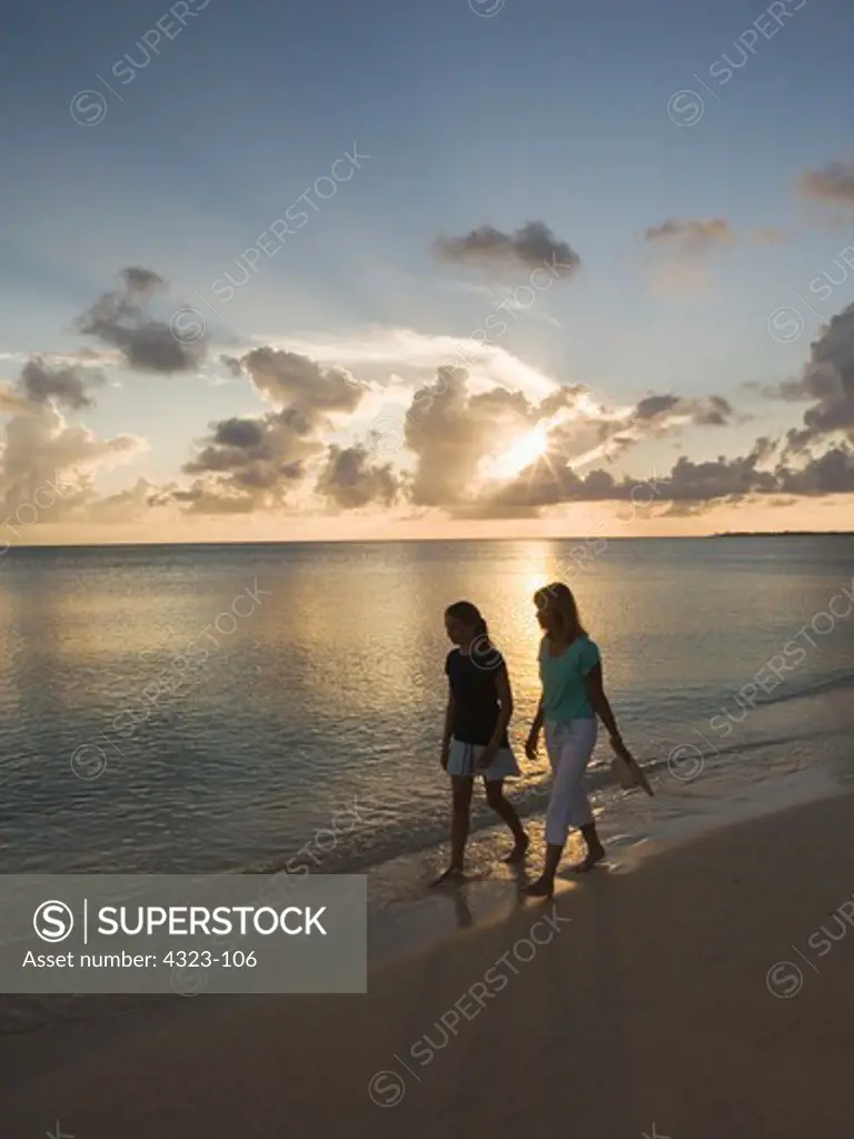 Mother and Daughter Stroll on a Beach at Sunset