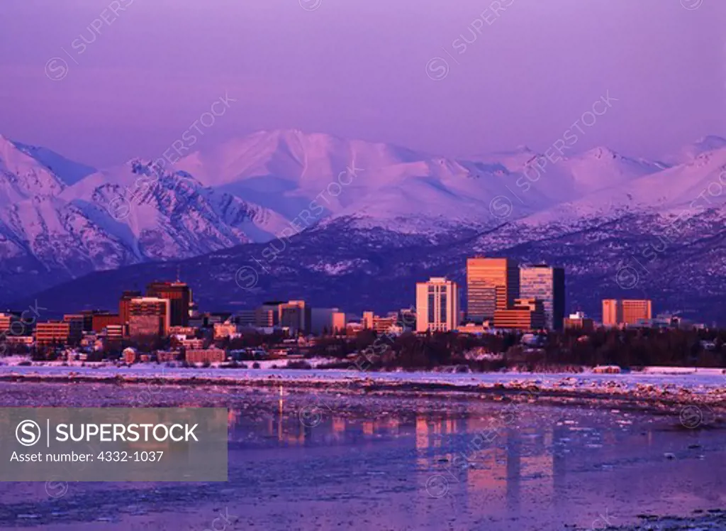 Skyline of Anchorage with the Chugach Mountains beyond viewed before sunset from Earthquake Park, Alaska.