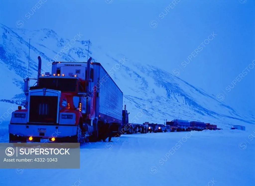 Truck traffic stopped pm the Dalton Highway in winter waiting for an avalanche to be cleared from Atigun Pass, north side of the Brooks Range, Alaska.